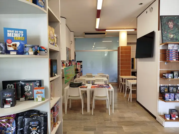 Scaffali di giochi e fumetti con la sala tavoli sullo sfondo